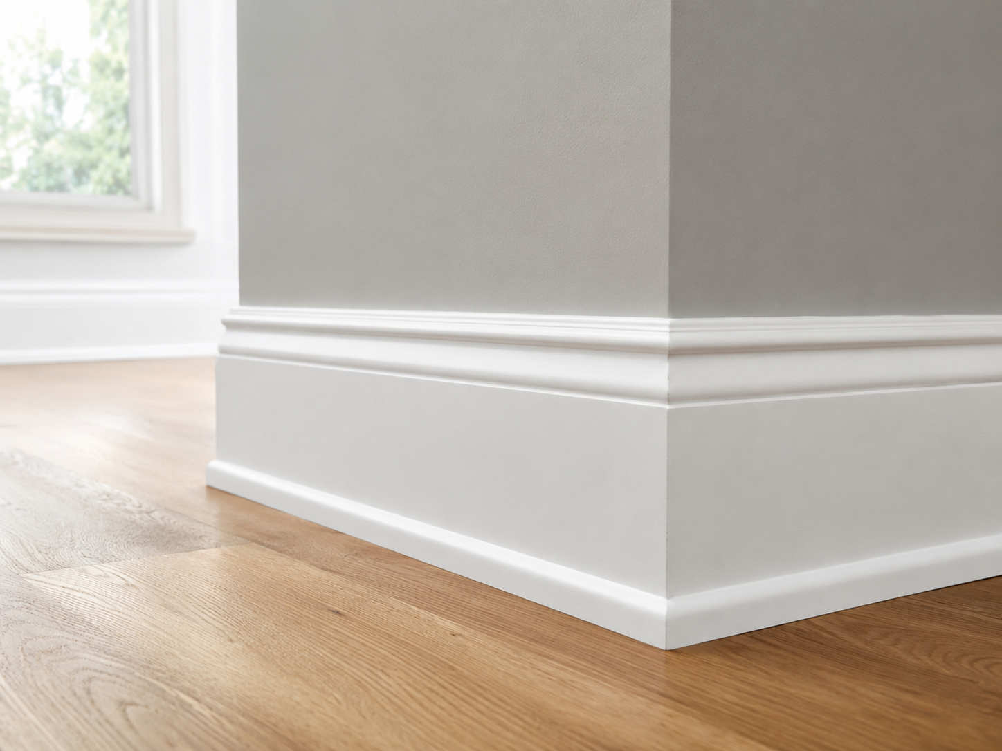 Close-up of crisp white baseboard trim meeting a freshly painted wall and clean hardwood floor.